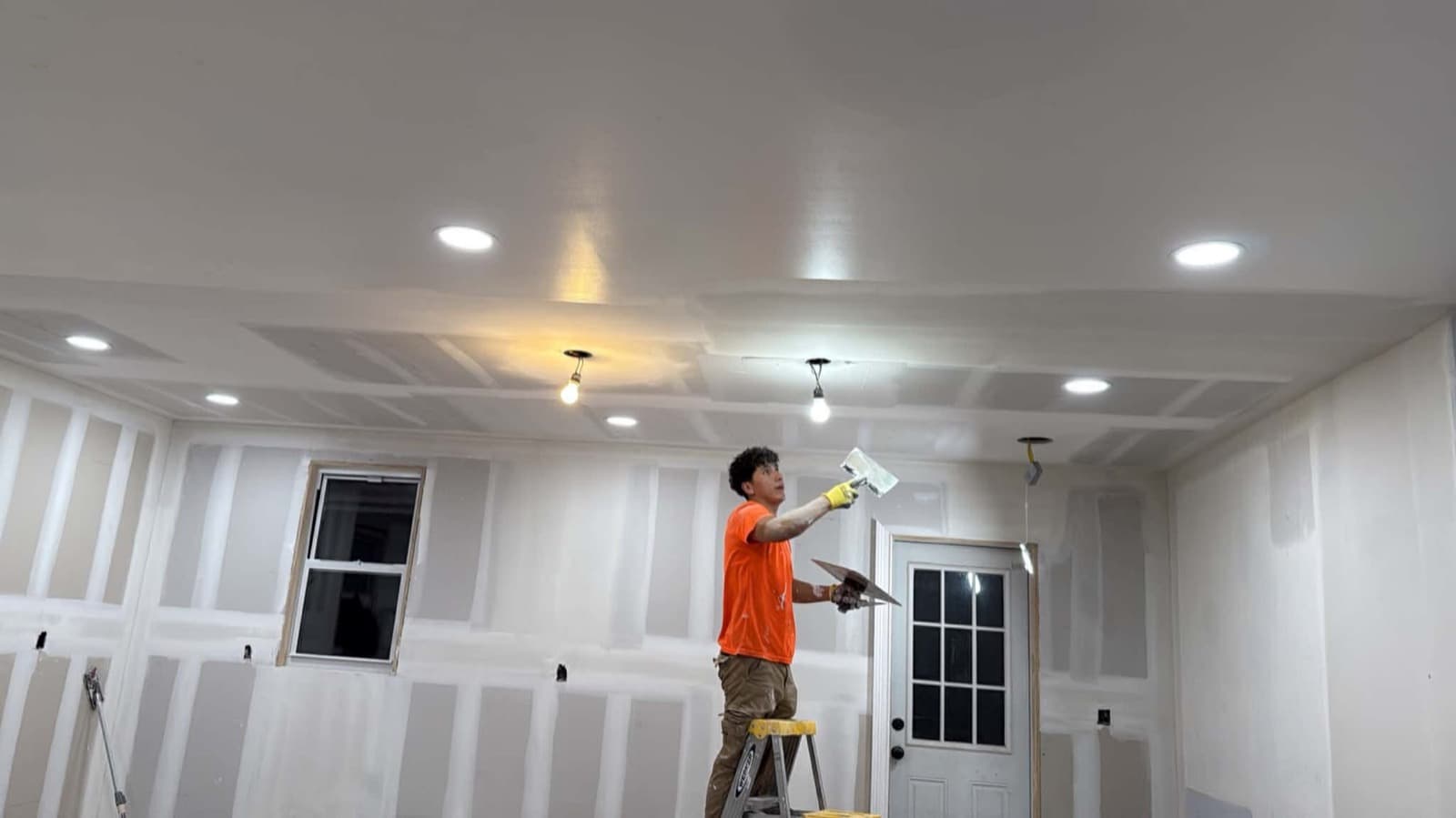 Worker preparing interior walls and ceiling during a property improvement project