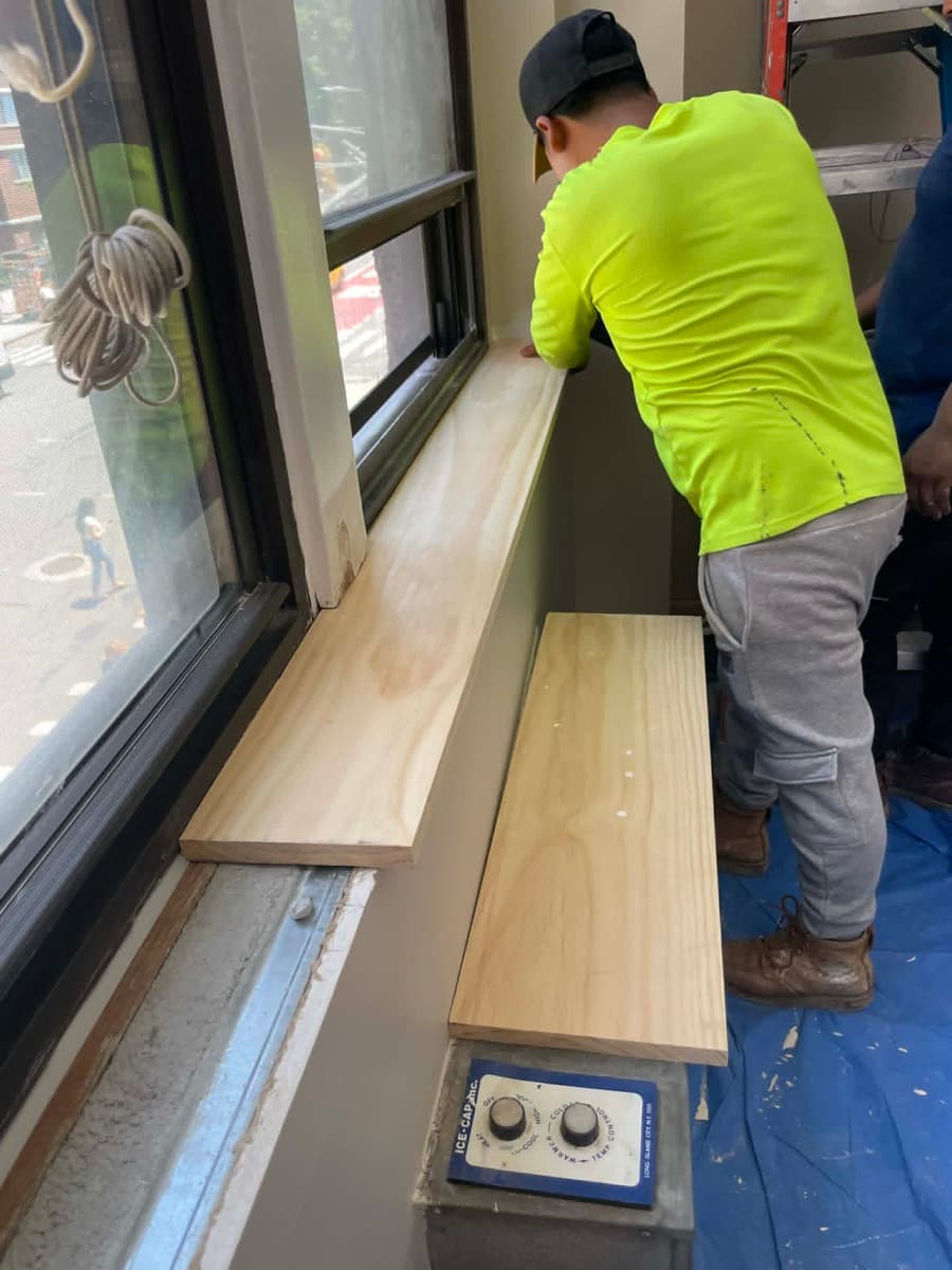 Hatun worker installing interior finish details beside a window