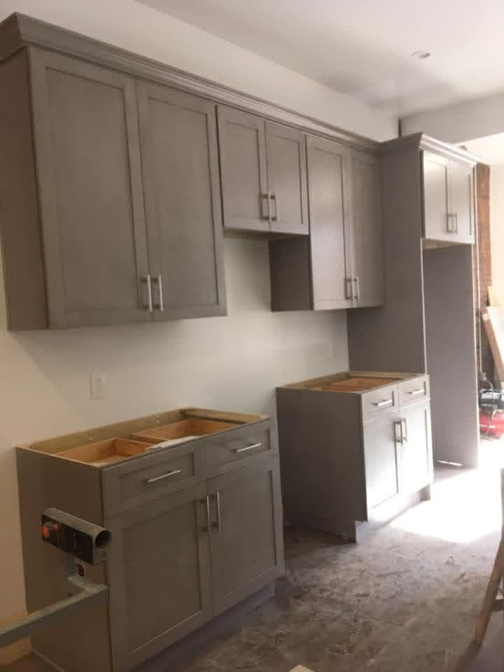 Gray upper and lower kitchen cabinets being installed during renovation