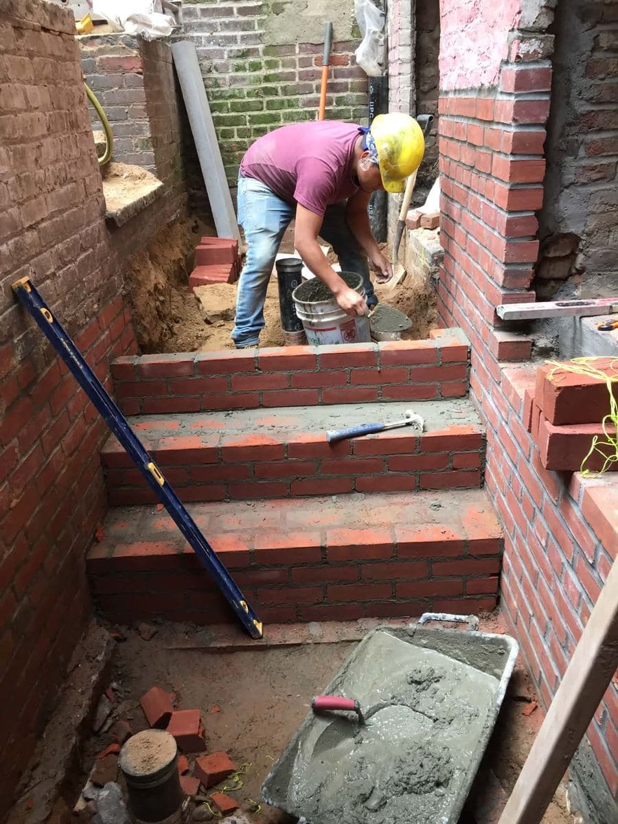 Crew building new brick steps between masonry walls