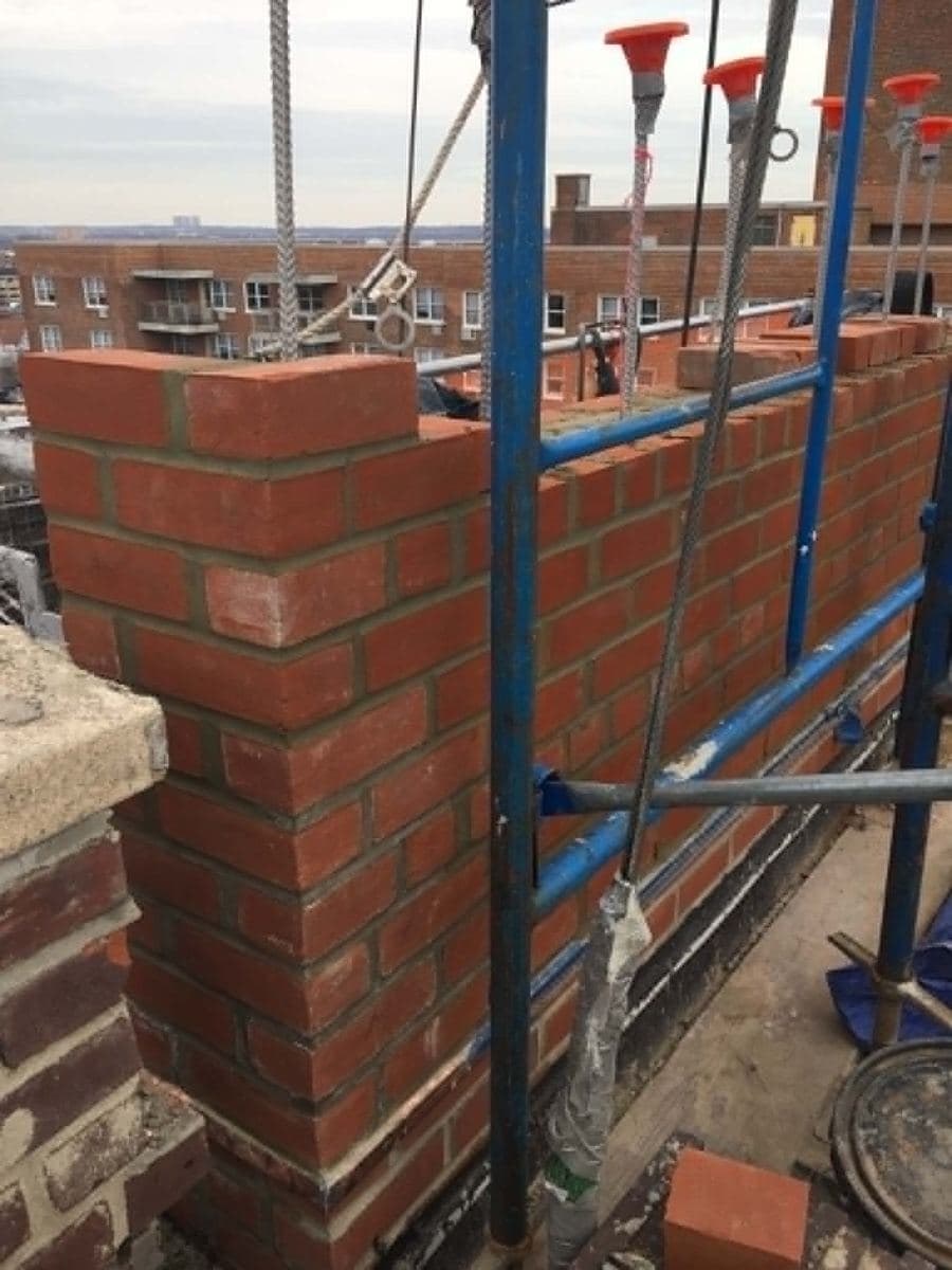 New brick wall courses under construction beside scaffolding