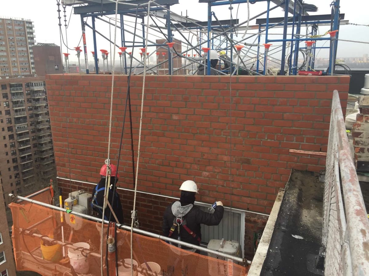 Brick facade work being completed from a supported access platform