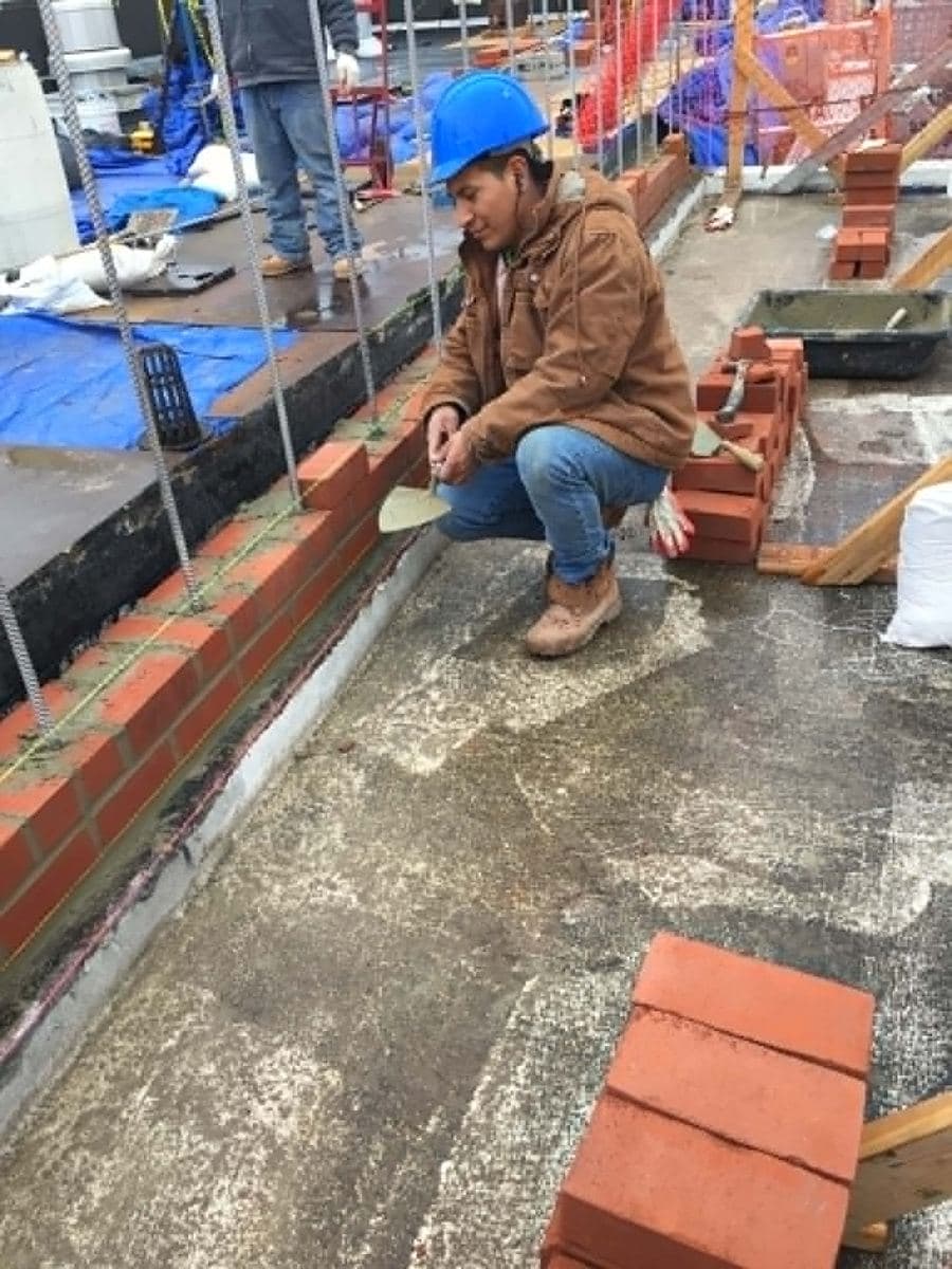 Mason kneeling with bricks during exterior masonry work