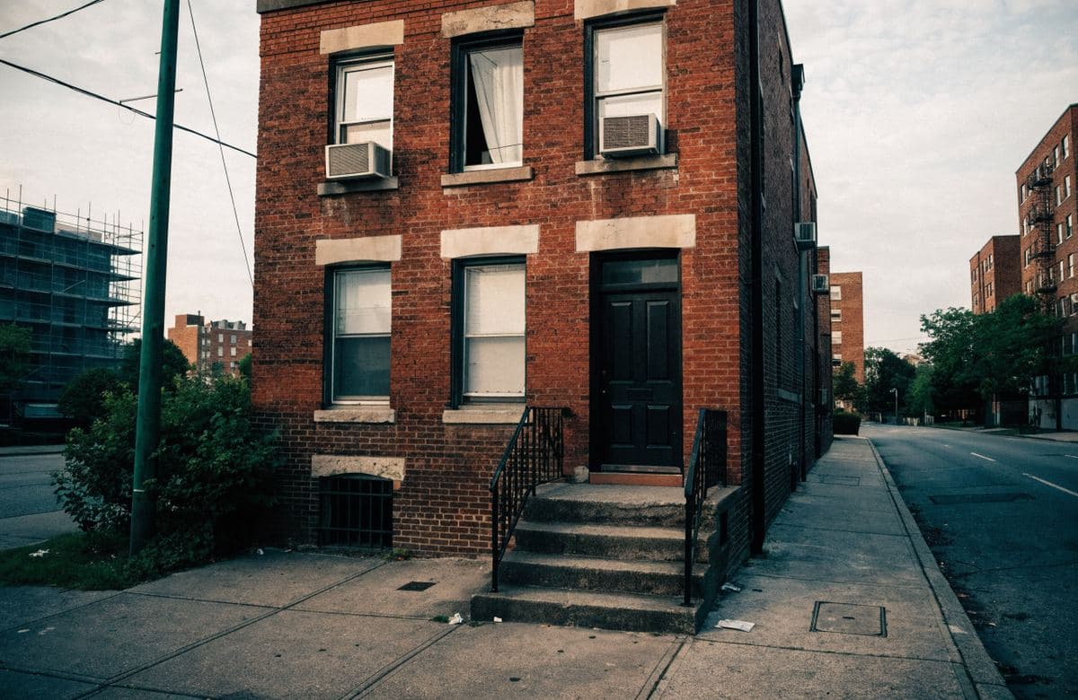 Illustrative small brick rental building with a masonry stoop