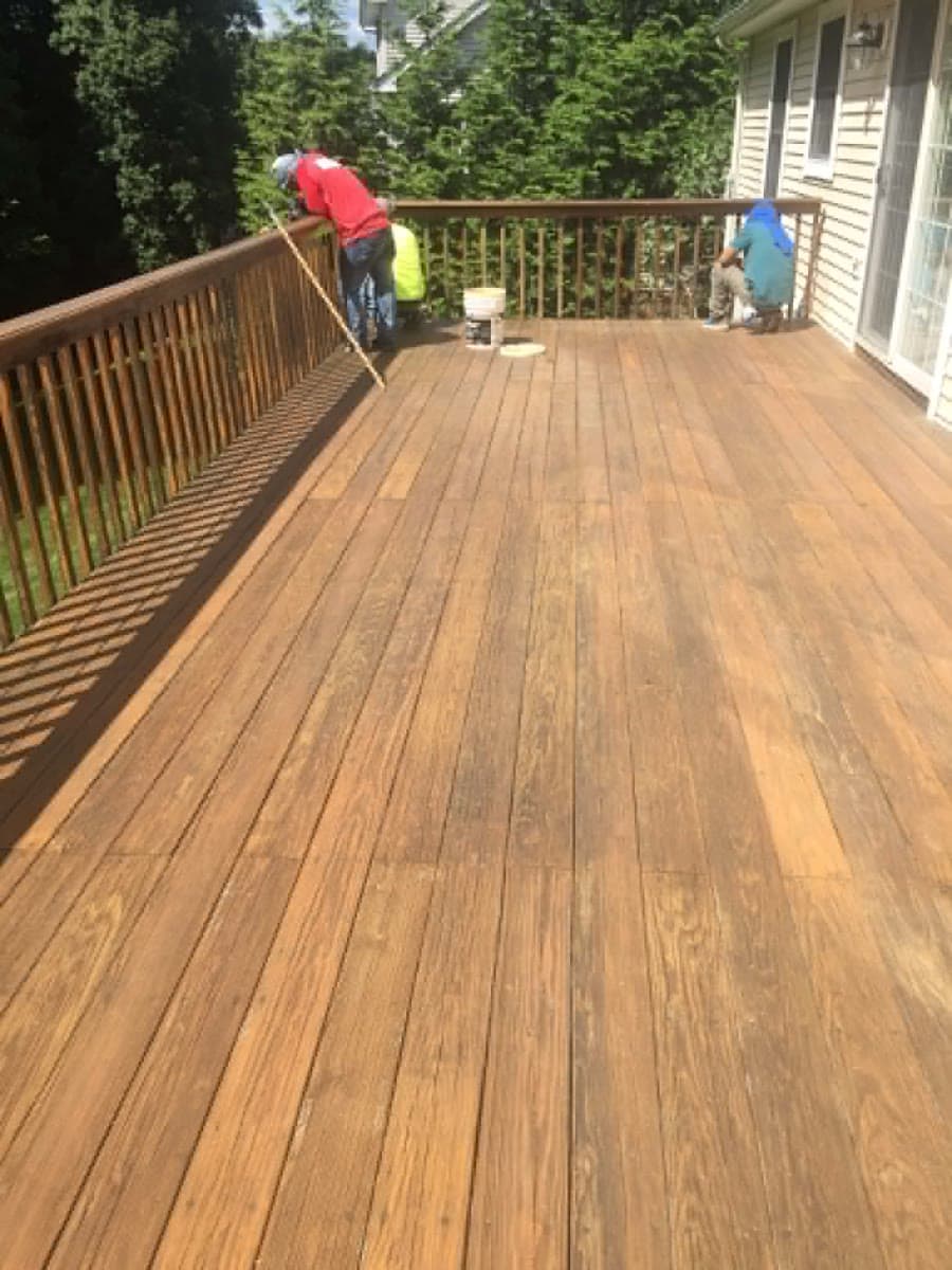 Crew applying an exterior finish to deck boards and railings