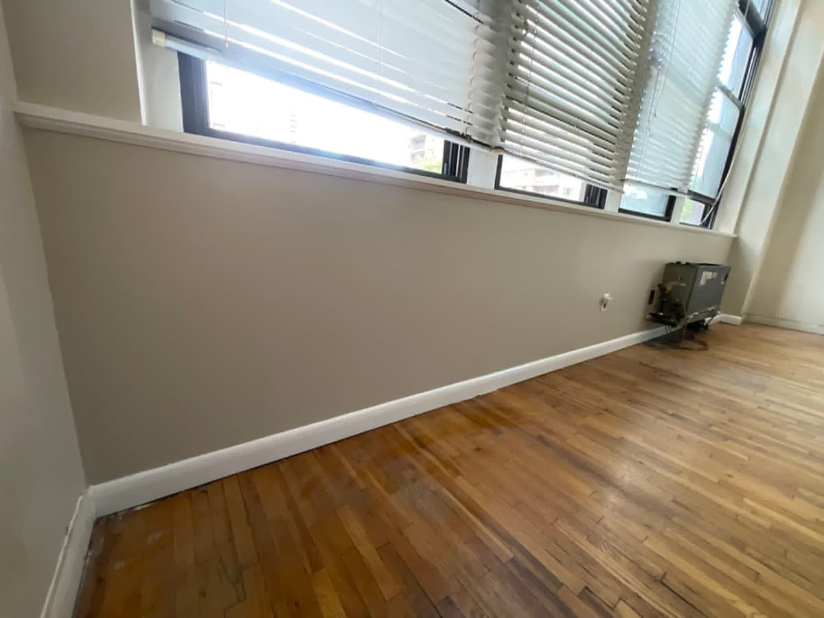 Freshly painted interior wall with clean trim and wood flooring