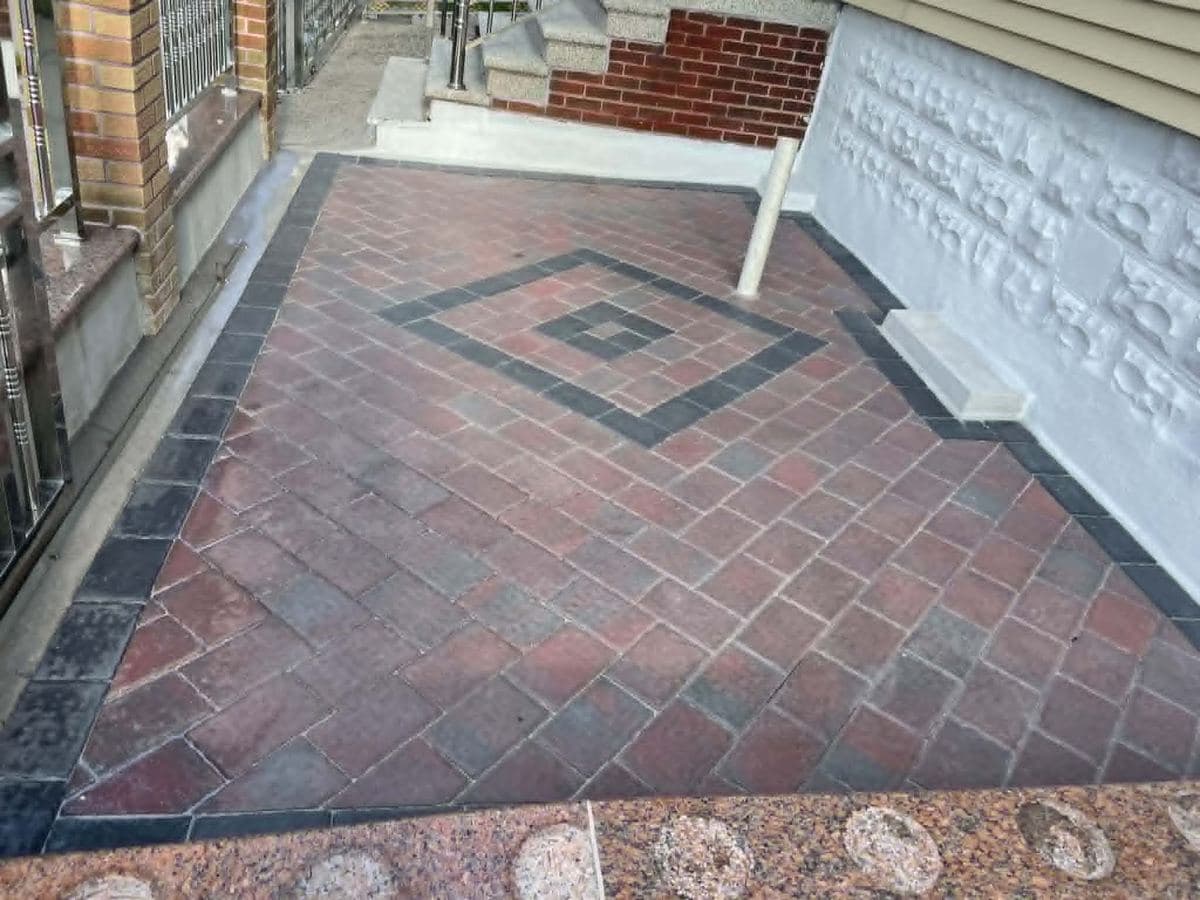Paver patio with a decorative inlaid pattern beside a residential building