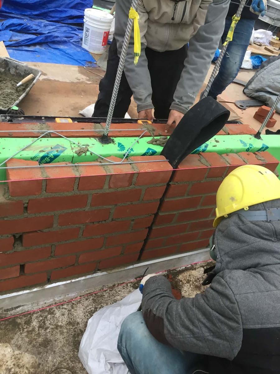 Crew finishing the top course and joints of a brick wall