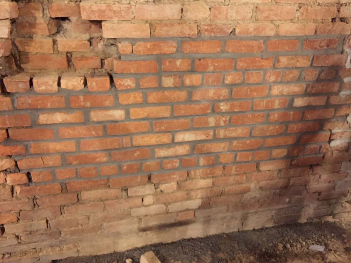 Deteriorated brick wall with failed mortar and loose units at the top