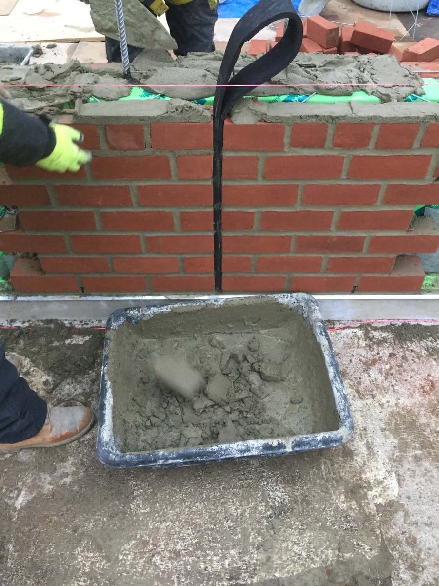Freshly mixed mortar prepared beside a red brick wall for joint work
