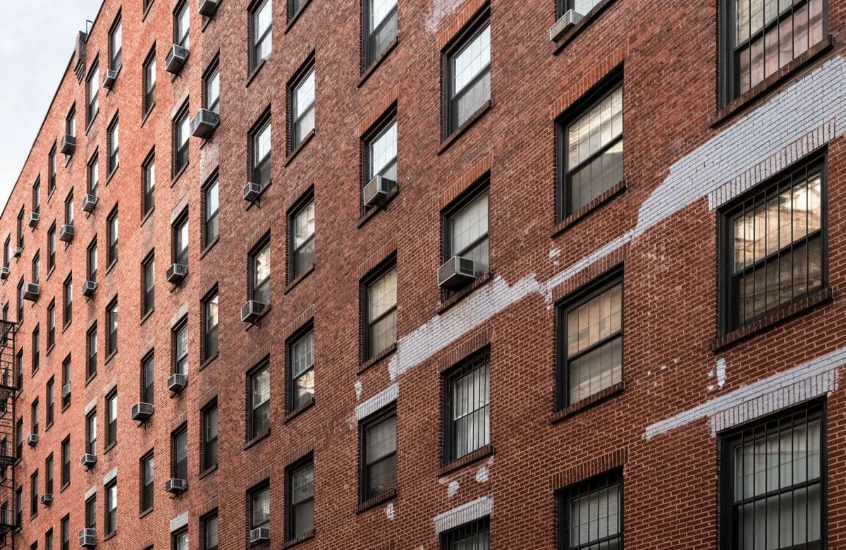 Illustrative tall brick apartment facade with sections of joint repair