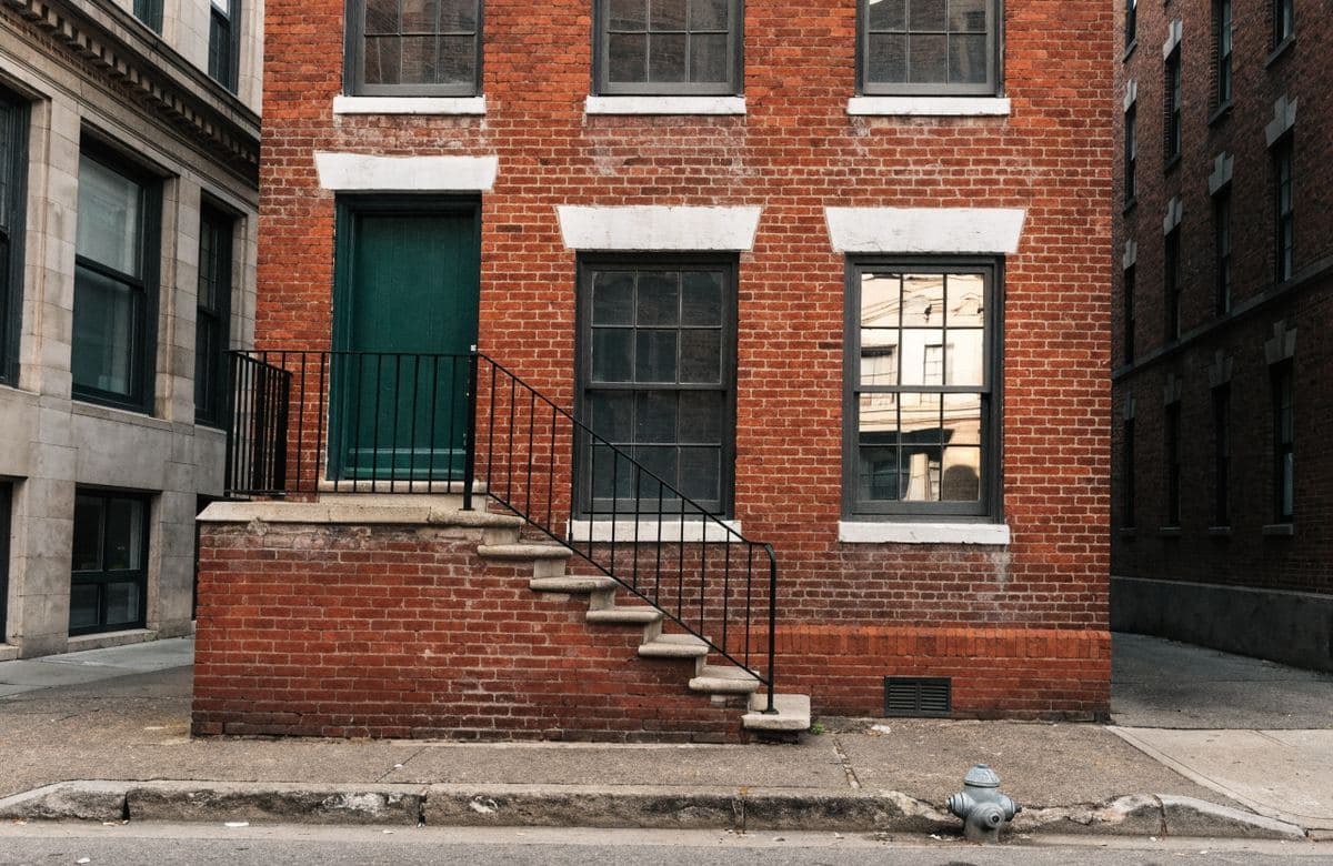 Illustrative small brick rental building with a stoop and repointed walls