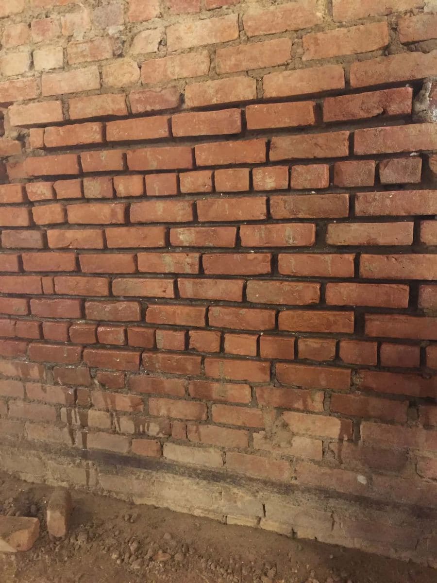 Aged brick wall with joints worn back from the face of the brick