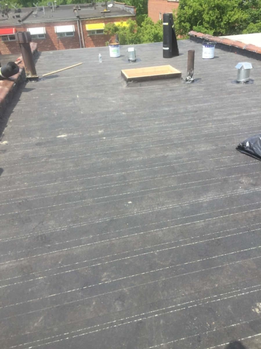 Flat roofing surface showing seams, roof penetrations and edge work